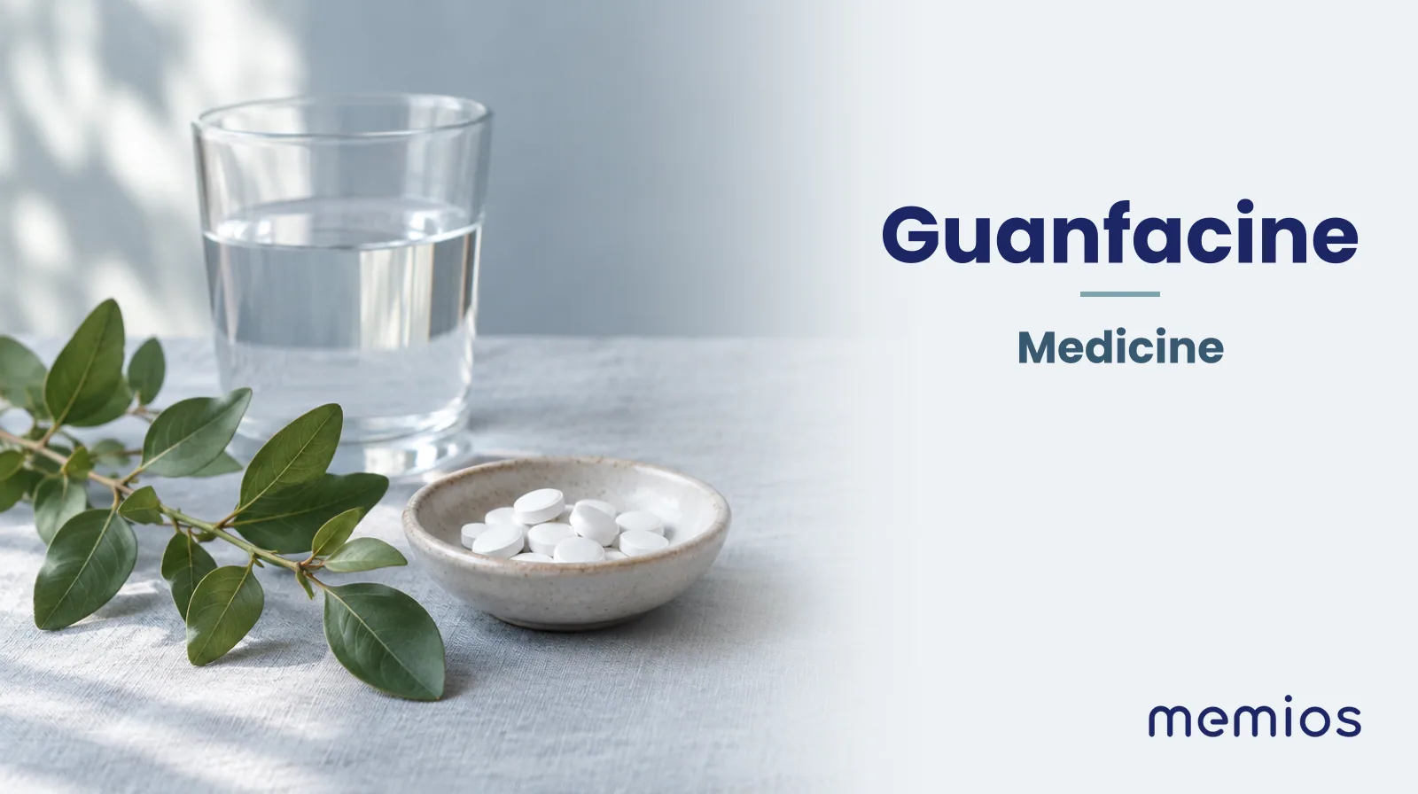 Photograph for Guanfacine: plain unmarked tablets in a dish beside a glass of water on pale linen.