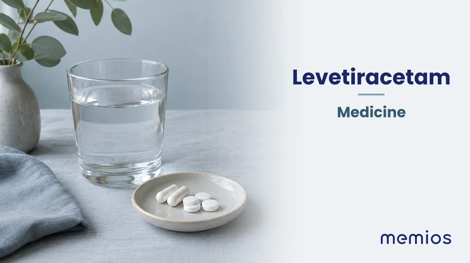 Photograph for Levetiracetam: plain unmarked tablets in a dish beside a glass of water on pale linen.