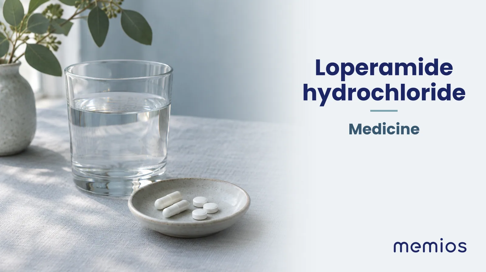 Photograph for Loperamide hydrochloride: plain unmarked tablets in a dish beside a glass of water on pale linen.