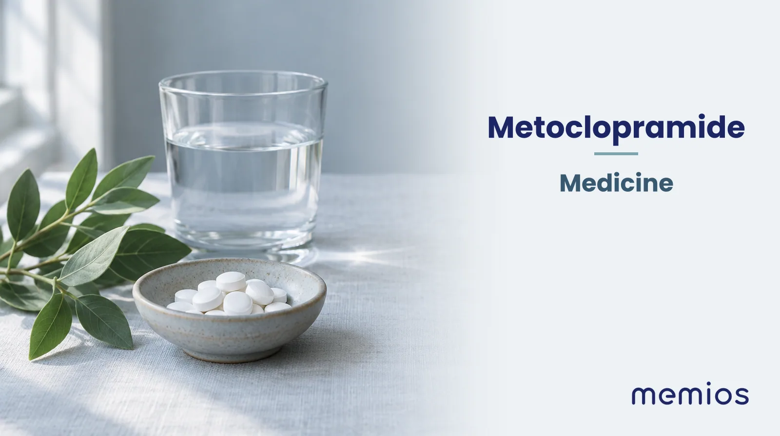 Photograph for Metoclopramide: plain unmarked tablets in a dish beside a glass of water on pale linen.
