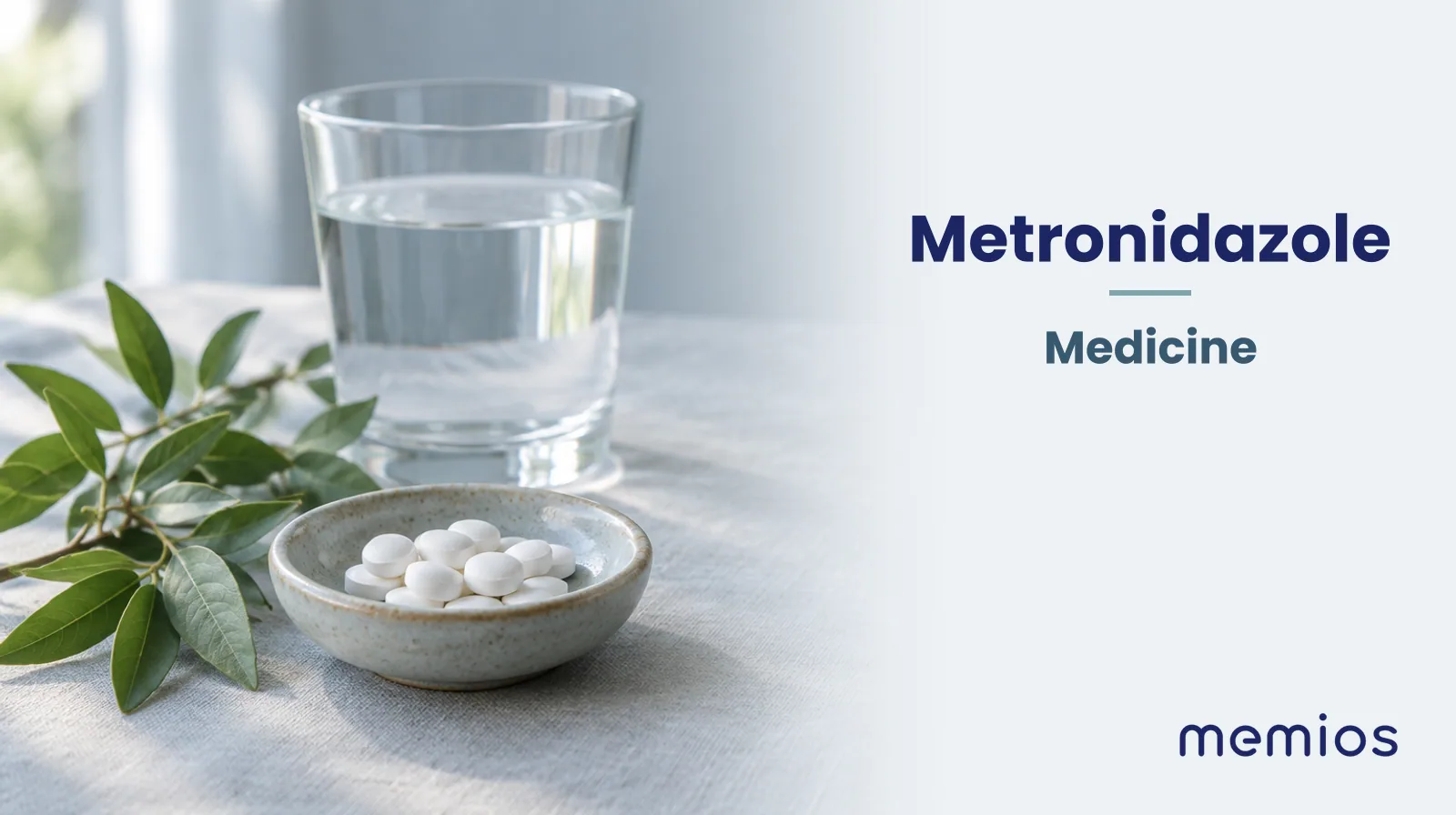 Photograph for Metronidazole: plain unmarked tablets in a dish beside a glass of water on pale linen.