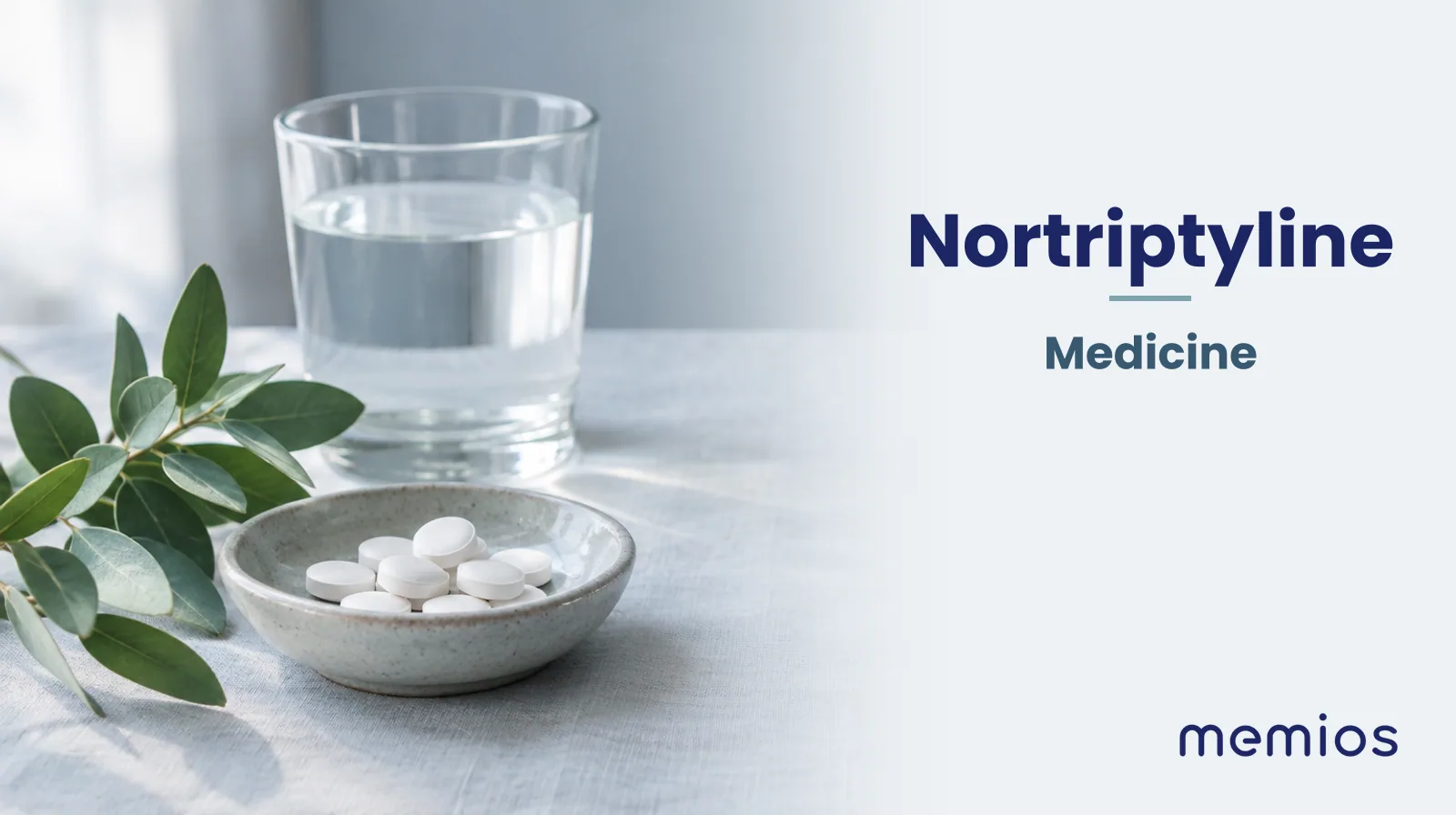 Photograph for Nortriptyline: plain unmarked tablets in a dish beside a glass of water on pale linen.