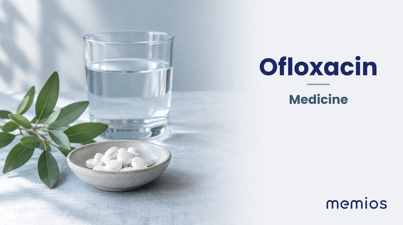 Photograph for Ofloxacin: plain unmarked tablets in a dish beside a glass of water on pale linen.