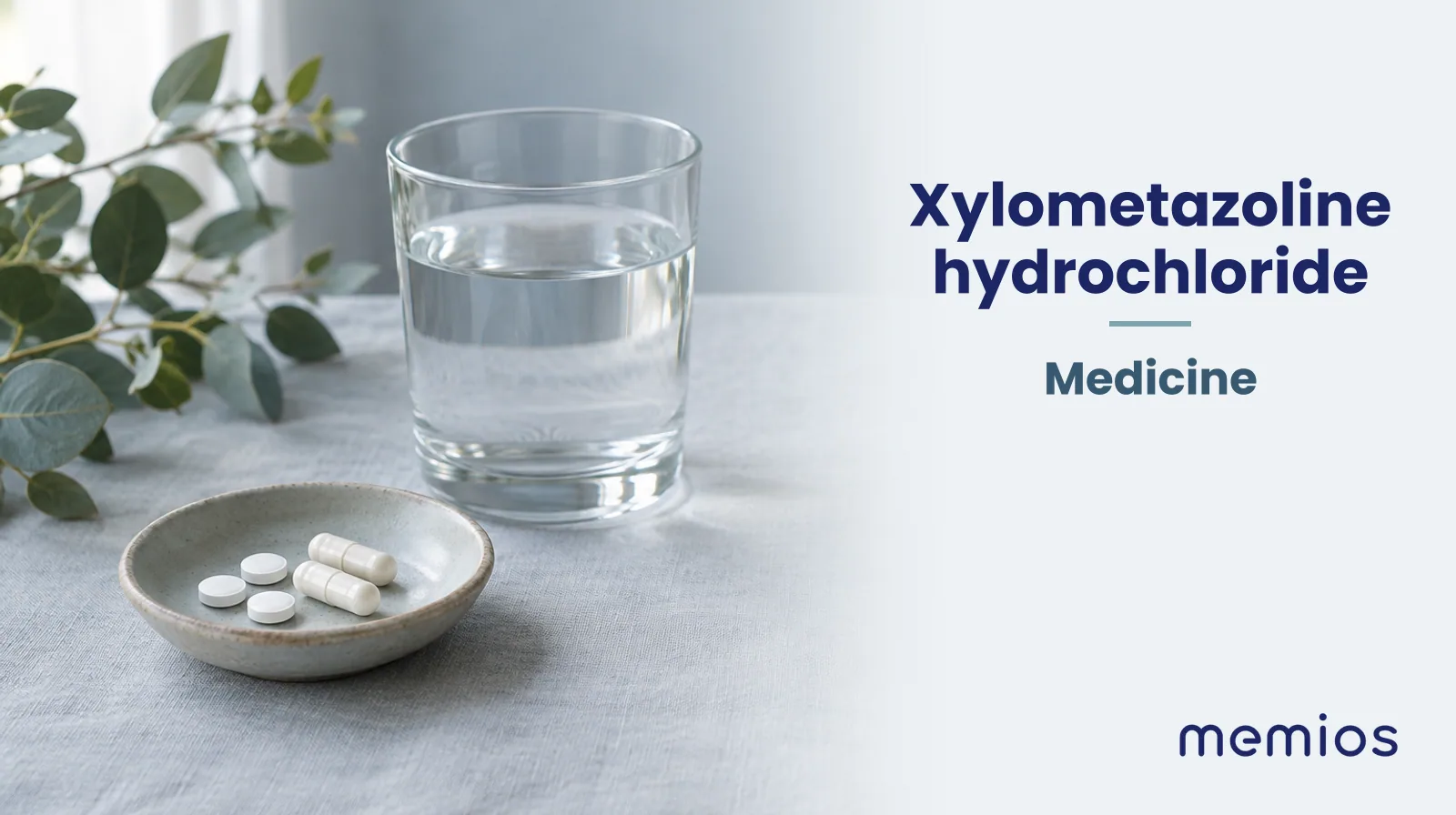 Photograph for Xylometazoline hydrochloride: plain unmarked tablets in a dish beside a glass of water on pale linen.